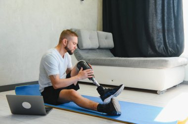 Adam internette egzersiz yapıyor. Bacağı kesilmiş, evde bacaklarını esnetiyor..