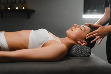 güzel bir genç kadın yalan rahat bir spa salonu ve alıcı yüz masajı.