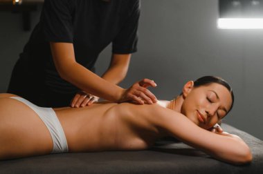 Masör spa salonundaki kadına masaj yapıyor..