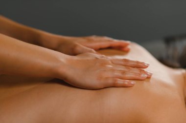 Masör masaj masasında yatan genç bir kadının sırtına ve omuzlarına masaj yapıyor. Masaj spa tedavisi kavramı.