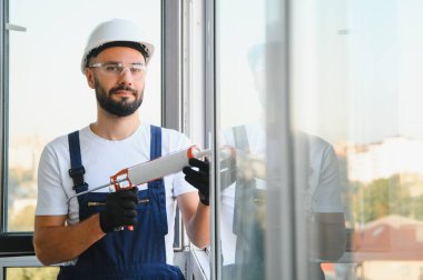 İnşaat işçisi plastik pencereyi tornavidayla tamir ediyor. Pankart tasarımı