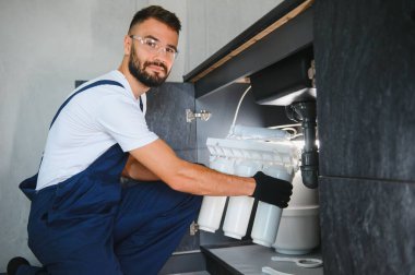 Tesisatçı su filtresi kurar ya da değiştirir. Yerleştirme su filtresi. Tamirci mutfağa su filtresi koyuyor. Ters osmoz su arıtma sisteminin kurulumu.