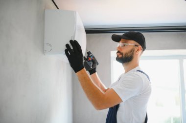 Üniformalı teknisyen havalandırmayı tamir ediyor. İnşaat ve onarım konsepti.