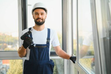 İnşaat işçisi plastik pencereyi tornavidayla tamir ediyor. Pankart tasarımı