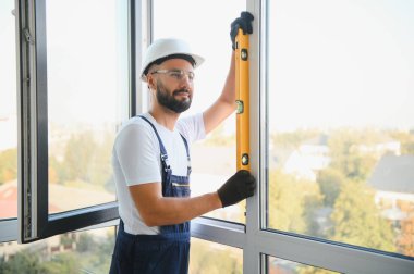 İnşaat işçisi plastik pencereyi tornavidayla tamir ediyor. Pankart tasarımı