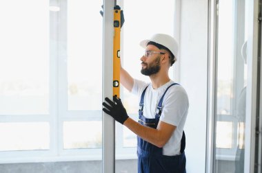 İnşaat işçisi plastik pencereyi tornavidayla tamir ediyor. Pankart tasarımı