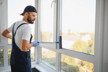 Profesyonel bir temizlik şirketinin çalışanı binanın camlarını yıkıyor. Dükkan ve işletmeler için vitrin temizliği.