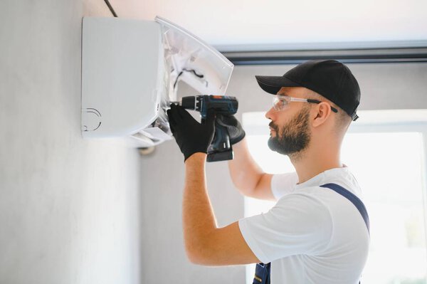 Technician man in uniform installing, repairing air conditioner. Construction and repair concept.