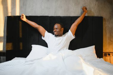 Yukarda, rahat gülümseyen Afro-Amerikan bir adamın portresi beyaz çarşafların üzerinde yatıyordu.