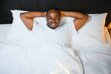 Yukarda, rahat gülümseyen Afro-Amerikan bir adamın portresi beyaz çarşafların üzerinde yatıyordu.