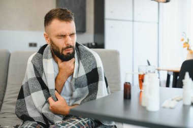 Hasta adam oturma odasında öksürürken göğsünü ağrı içinde tutuyor. Boğaz ağrısı ve öksürük, akciğer ağrısı olan bir adam, sağlık sorunları konsepti..