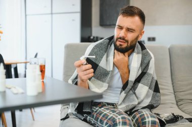 Hasta adam oturma odasında öksürürken göğsünü ağrı içinde tutuyor. Boğaz ağrısı ve öksürük, akciğer ağrısı olan bir adam, sağlık sorunları konsepti..