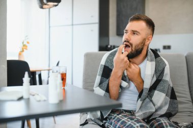 Rhinitis, ilaç ve sağlık konsepti - evde ağız spreyi kullanan hasta adam.
