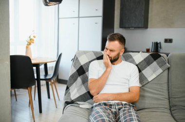 Evde acı çeken hassas dişleri olan bir adam..