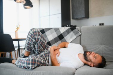 Mide ağrısı, evde karın ağrısı olan bir adam, sağlık sorunları konsepti..