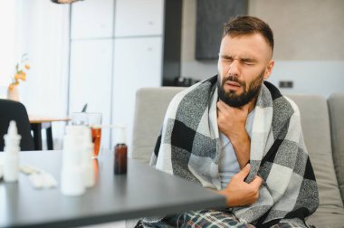 Hasta adam oturma odasında öksürürken göğsünü ağrı içinde tutuyor. Boğaz ağrısı ve öksürük, akciğer ağrısı olan bir adam, sağlık sorunları konsepti..