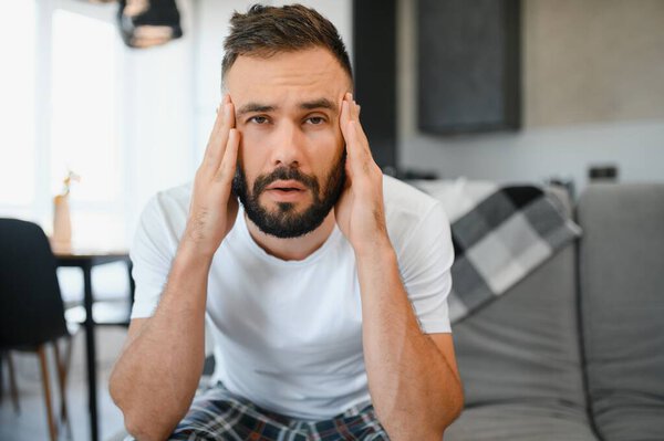 Молодой человек, страдающий сильной головной болью или мигренью, на следующее утро после похмелья.