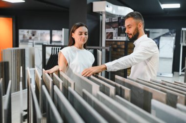 Satıcı ve bayan bir müşteri evi için seramik bir fayans seçiyorlar, ev tasarımı mağazasında..