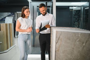 Satıcı ve bayan bir müşteri evi için seramik bir fayans seçiyorlar, ev tasarımı mağazasında..