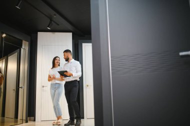 Bir satıcı, bir hırdavatçıda kadın müşteriye iç kapı seçimini tavsiye eder..