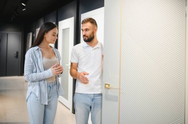 Hırdavatçıda alışveriş yapan genç adam ve kadının portresi farklı kapı seçenekleri seçiyor..