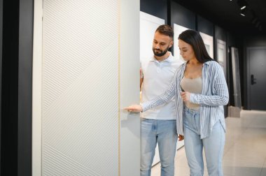 Evli bir çift, hırdavatçıdaki evleri için yeni iç kapılar seçiyor..