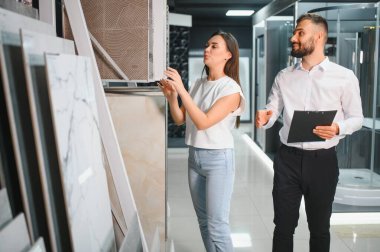 Pazarda fayans seçen pazarlamacı ile genç bir kadın..