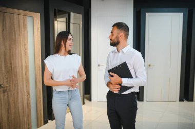 Hırdavatçıda alışveriş yapan gülümseyen genç bir kadının portresi farklı kapı seçenekleri seçiyor. Erkek danışman seçiminde yardımcı olur.