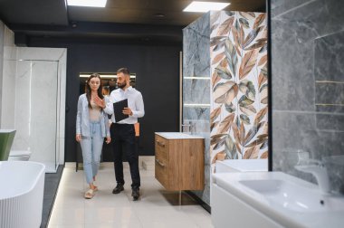 Pazarda fayans seçen pazarlamacı ile genç bir kadın..