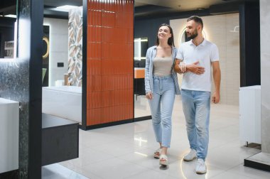 Genç çift, tesisat dükkanında bir sürü hijyenik eşya olan banyo mobilyalarını seçiyor..