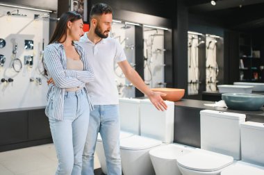 Genç çift, inşaat atölyesinde seramik eşliğinde birlikte duran tuvaleti seçiyor..