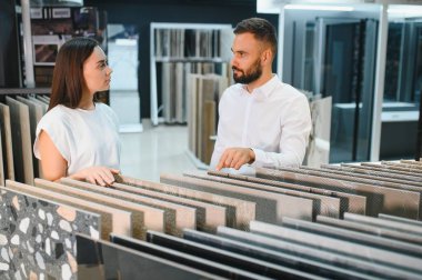 Satıcı ve bayan bir müşteri evi için seramik bir fayans seçiyorlar, ev tasarımı mağazasında..