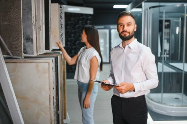 Pazarda fayans seçen pazarlamacı ile genç bir kadın..