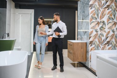 Pazarda fayans seçen pazarlamacı ile genç bir kadın..