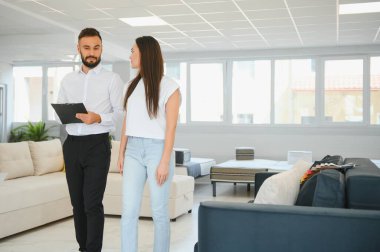 Satıcı mobilya dükkanındaki kadın müşteriye açıklama yapıyor..