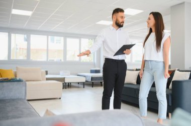 Mobilya mağazasında satış danışmanı, kadın müşteriye seçme şansı sunar..