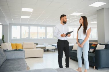 Mobilya mağazasında satış danışmanı, kadın müşteriye seçme şansı sunar..