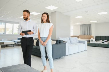 Genç bir satıcı mobilya mağazasında bir kadına danışıyor..
