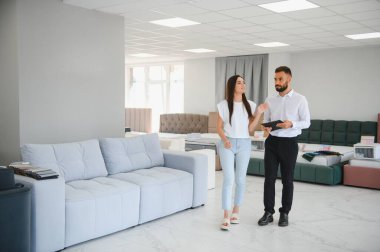 Satıcı mobilya dükkanındaki kadın müşteriye açıklama yapıyor..