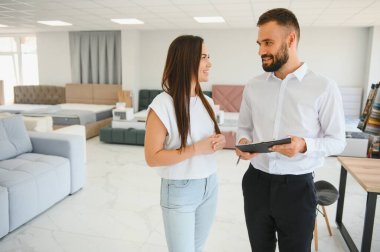 Satıcı mobilya dükkanındaki kadın müşteriye açıklama yapıyor..