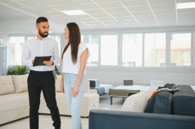 Profesyonel bir satış danışmanı bir mobilya mağazasında bir müşteriye tavsiyede bulunur