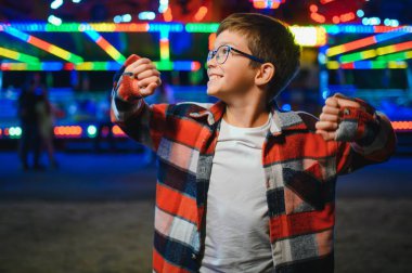 Yakışıklı ve mutlu bir çocuk lunaparkta eğleniyor..
