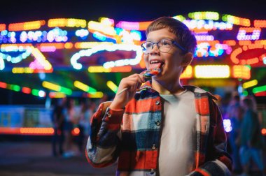 Beyaz bir çocuk, bir çocuk, eğlence parkına eğlenmek, oynamak ve atlıkarıncaya binmek için geldi. Atlıkarıncanın önünde duran bir çocuk.