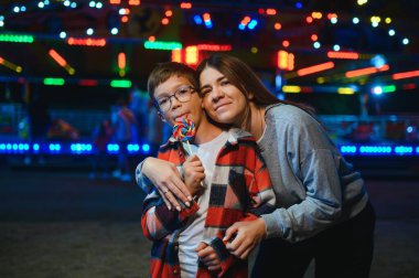 Yakışıklı bir çocuk annesiyle birlikte lunaparka eğlenmeye ve atlıkarıncalara ve salıncaklara binmeye geldi..