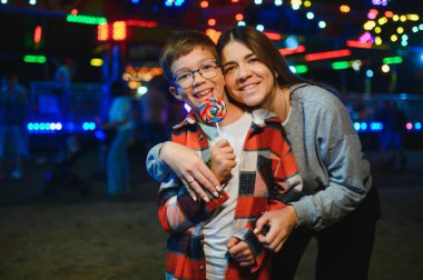 Yakışıklı bir çocuk annesiyle birlikte lunaparka eğlenmeye ve atlıkarıncalara ve salıncaklara binmeye geldi..