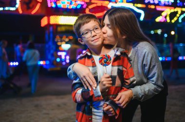 Yakışıklı bir çocuk annesiyle birlikte lunaparka eğlenmeye ve atlıkarıncalara ve salıncaklara binmeye geldi..
