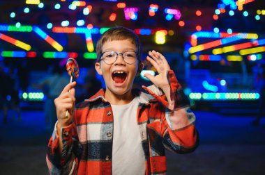 Beyaz bir çocuk, bir çocuk, eğlence parkına eğlenmek, oynamak ve atlıkarıncaya binmek için geldi. Atlıkarıncanın önünde duran bir çocuk.