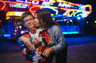 Yakışıklı bir çocuk annesiyle birlikte lunaparka eğlenmeye ve atlıkarıncalara ve salıncaklara binmeye geldi..