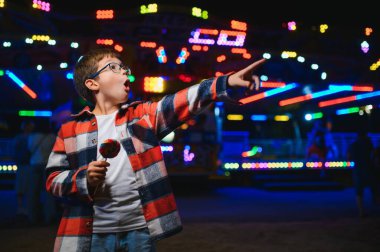 Beyaz bir çocuk, bir çocuk, eğlence parkına eğlenmek, oynamak ve atlıkarıncaya binmek için geldi. Atlıkarıncanın önünde duran bir çocuk.