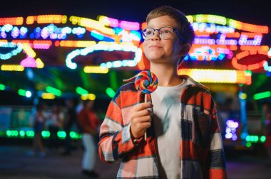 Beyaz bir çocuk, bir çocuk, eğlence parkına eğlenmek, oynamak ve atlıkarıncaya binmek için geldi. Atlıkarıncanın önünde duran bir çocuk.